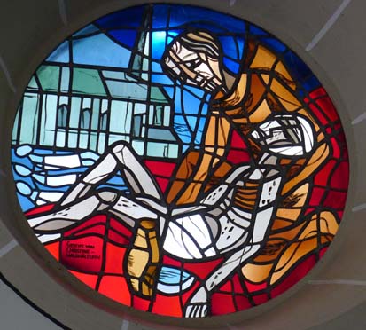 Glasfenster in der heutigen Kapelle mit einem Krankenpflegemotiv, im Hintergrund die Kirche der Pfarrei Kärlich, zu der die Kapelle seit jeher gehört